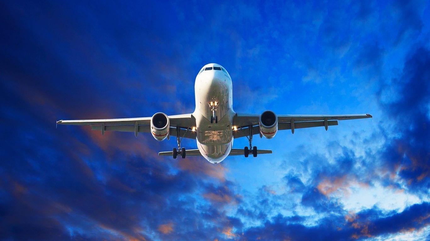 flying cargo plane over shipping port behind